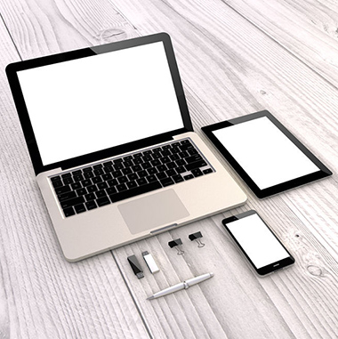 Laptop, tablet, phone, and accessories on a gray woodgrain floor